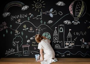 Young girl drawing on a on a chalk board, creating a passion board