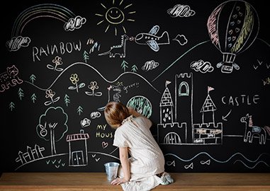 Young girl drawing on a on a chalk board, creating a passion board