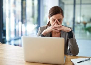 Atressed woman with limiting beliefs about money sitting in front of a computer
