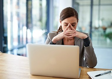 Atressed woman with limiting beliefs about money sitting in front of a computer